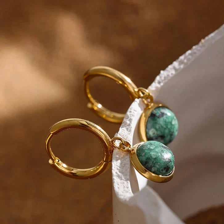 The Green Stone Charm Hoop Earrings exude majesty and elegance, reminiscent of the legendary stone of the African queen. Each green stone is delicately cut to enhance its natural beauty and vibrant hue, adding a touch of exoticism and sophistication to your look.