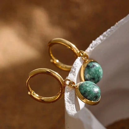 The Green Stone Charm Hoop Earrings exude majesty and elegance, reminiscent of the legendary stone of the African queen. Each green stone is delicately cut to enhance its natural beauty and vibrant hue, adding a touch of exoticism and sophistication to your look.