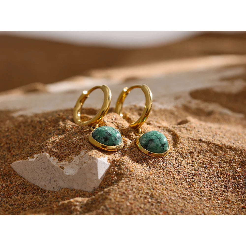 The Green Stone Charm Hoop Earrings exude majesty and elegance, reminiscent of the legendary stone of the African queen. Each green stone is delicately cut to enhance its natural beauty and vibrant hue, adding a touch of exoticism and sophistication to your look.