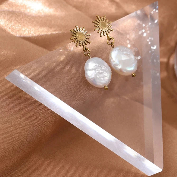 Radiate elegance with our Sun and Freshwater Pearl Earrings. Featuring a sun-shaped design and natural freshwater pearls, these 18k gold-plated, hypoallergenic stainless steel earrings exude positive energy and timeless beauty. Perfect for any occasion.