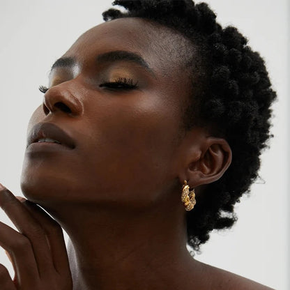 Model wearing Gorgeous Twisted Hoop Earrings, showcasing their elegant twisted design and dazzling shine from the studded zirconias, made from sustainable stainless steel with 18k gold plating