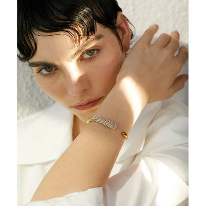  Elevate your elegance with our Pearl Accent Cuff Bracelet - Timeless Sophistication. Crafted from hypoallergenic stainless steel with sustainable 18k gold plating. Featuring simulated pearls for a touch of timeless elegance. Versatile design for all occasions.