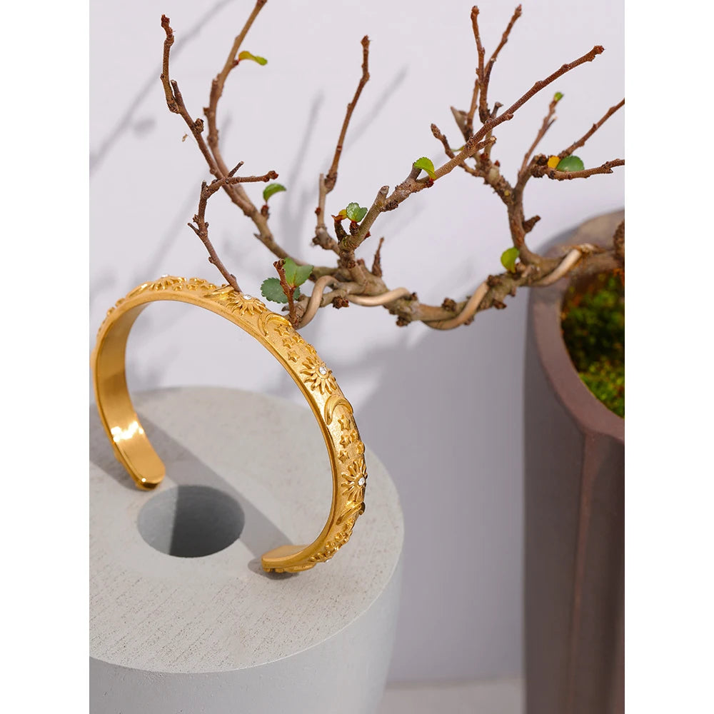 Celestial Cuff Bracelet - Cosmic Elegance. Crafted from hypoallergenic stainless steel, finished with durable 18k gold plating. Adorned with celestial designs symbolizing the sun, moon, and stars. Versatile and charming, designed for enduring comfort and style.