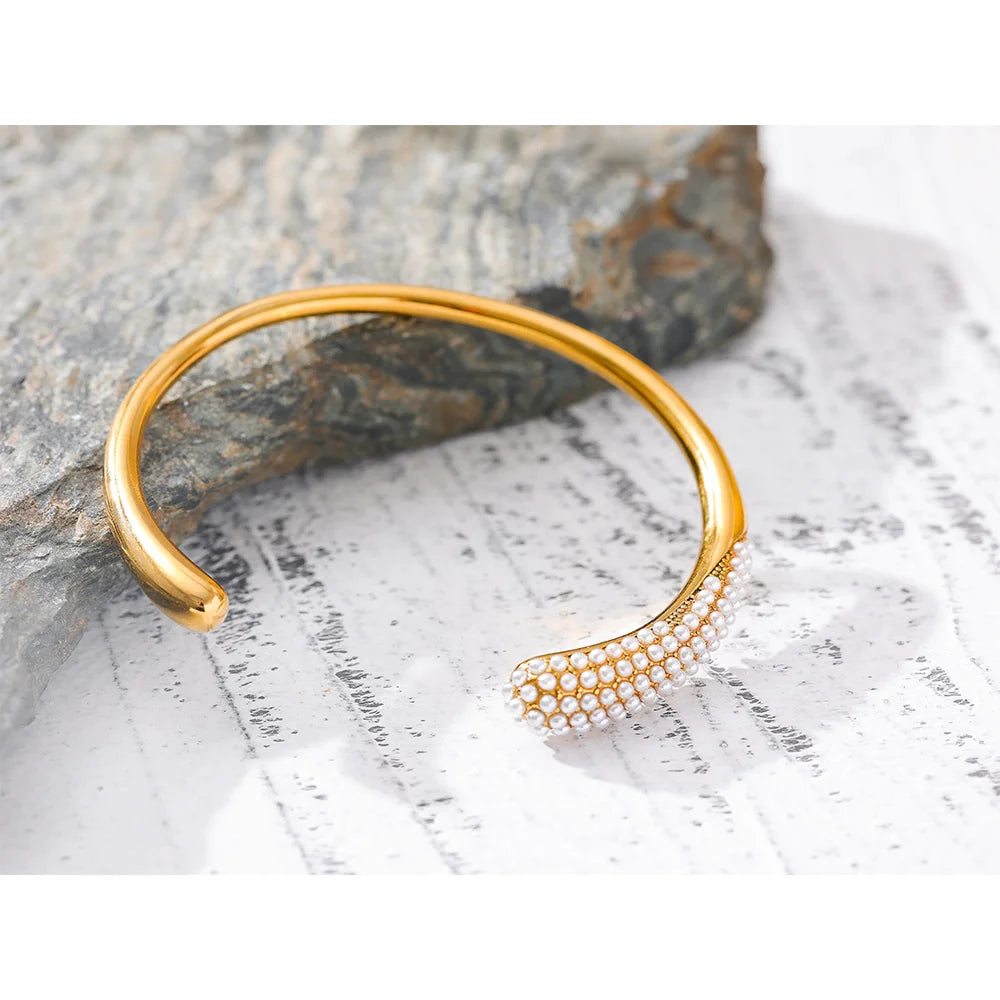  Elevate your elegance with our Pearl Accent Cuff Bracelet - Timeless Sophistication. Crafted from hypoallergenic stainless steel with sustainable 18k gold plating. Featuring simulated pearls for a touch of timeless elegance. Versatile design for all occasions.