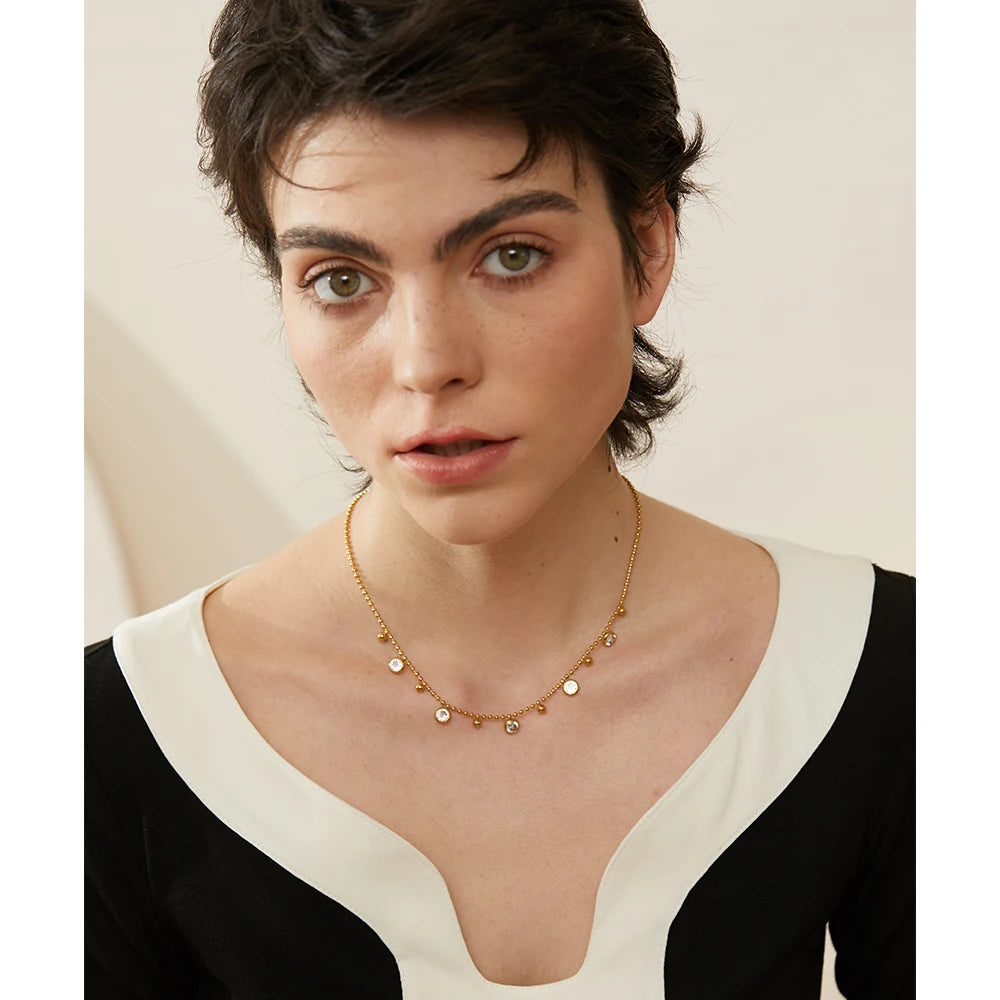 Model wearing the Necklace with Spherical Pendants and Circular Zirconias, showcasing its refined elegance and sophisticated radiance, made from sustainable materials with 18k gold plating