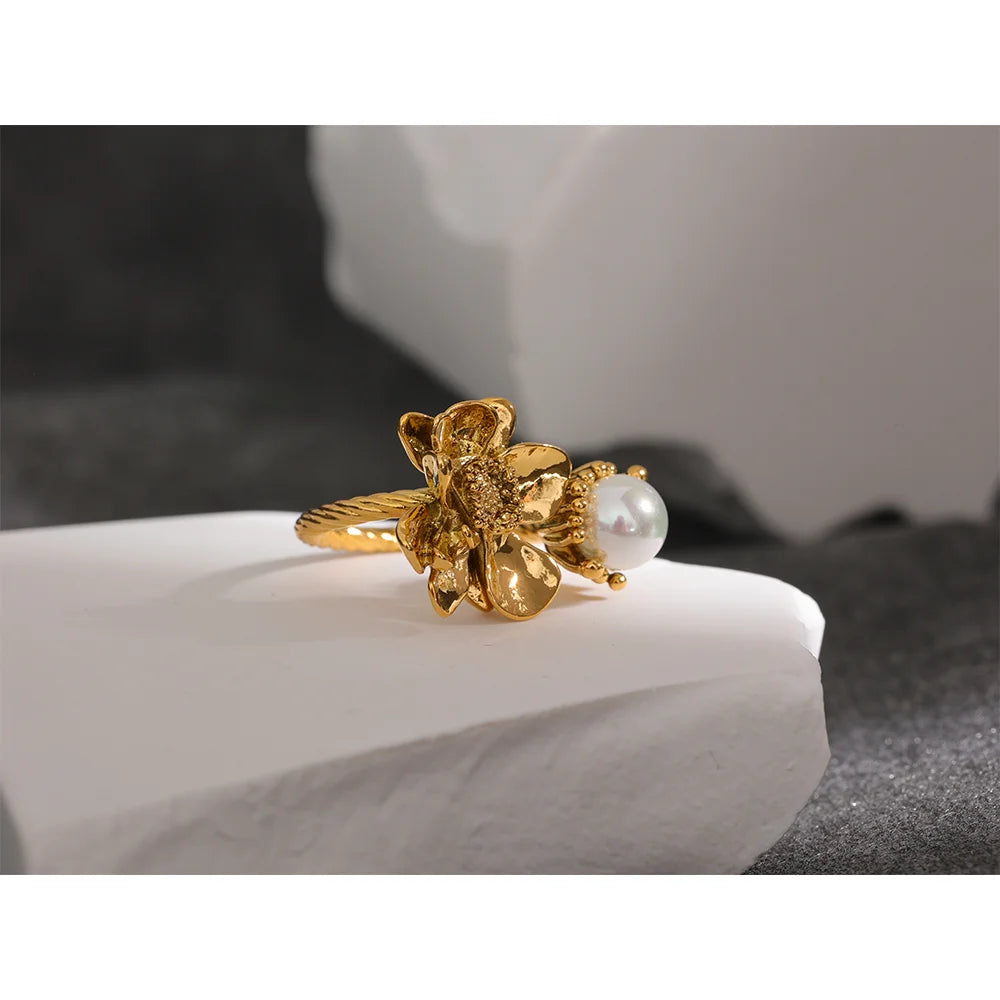 Elevate your elegance with our Pearl Flower Ring - Timeless Charm. Crafted from hypoallergenic stainless steel with sustainable 18k gold plating. Delicate floral design featuring a central simulated pearl for classic beauty. Comfortable and enduring for all occasions.